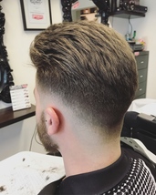 valentino style Low tight Skin fade with heavy textured slick back pomp